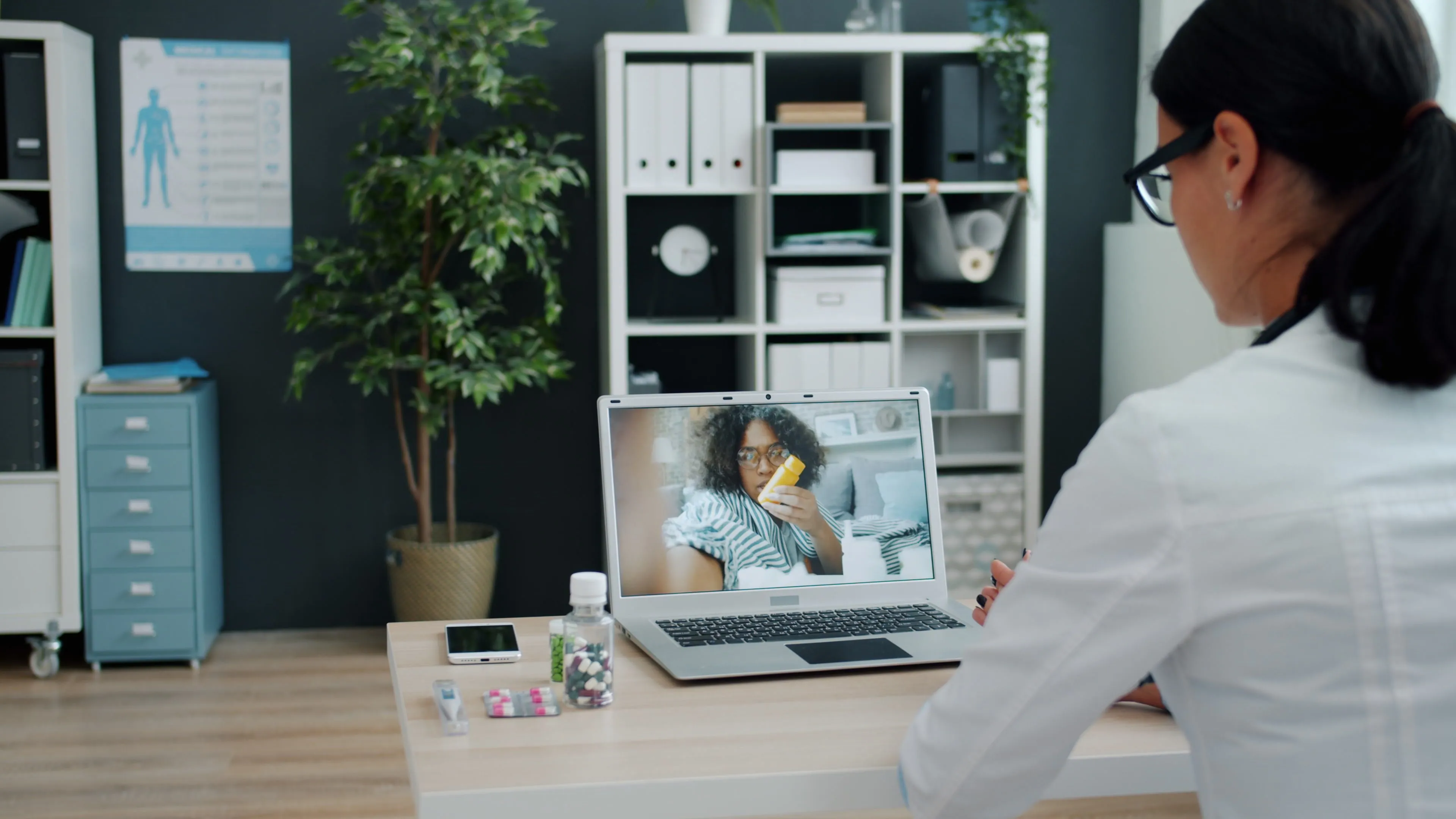 A doctor sits at a computer consulting with a client.