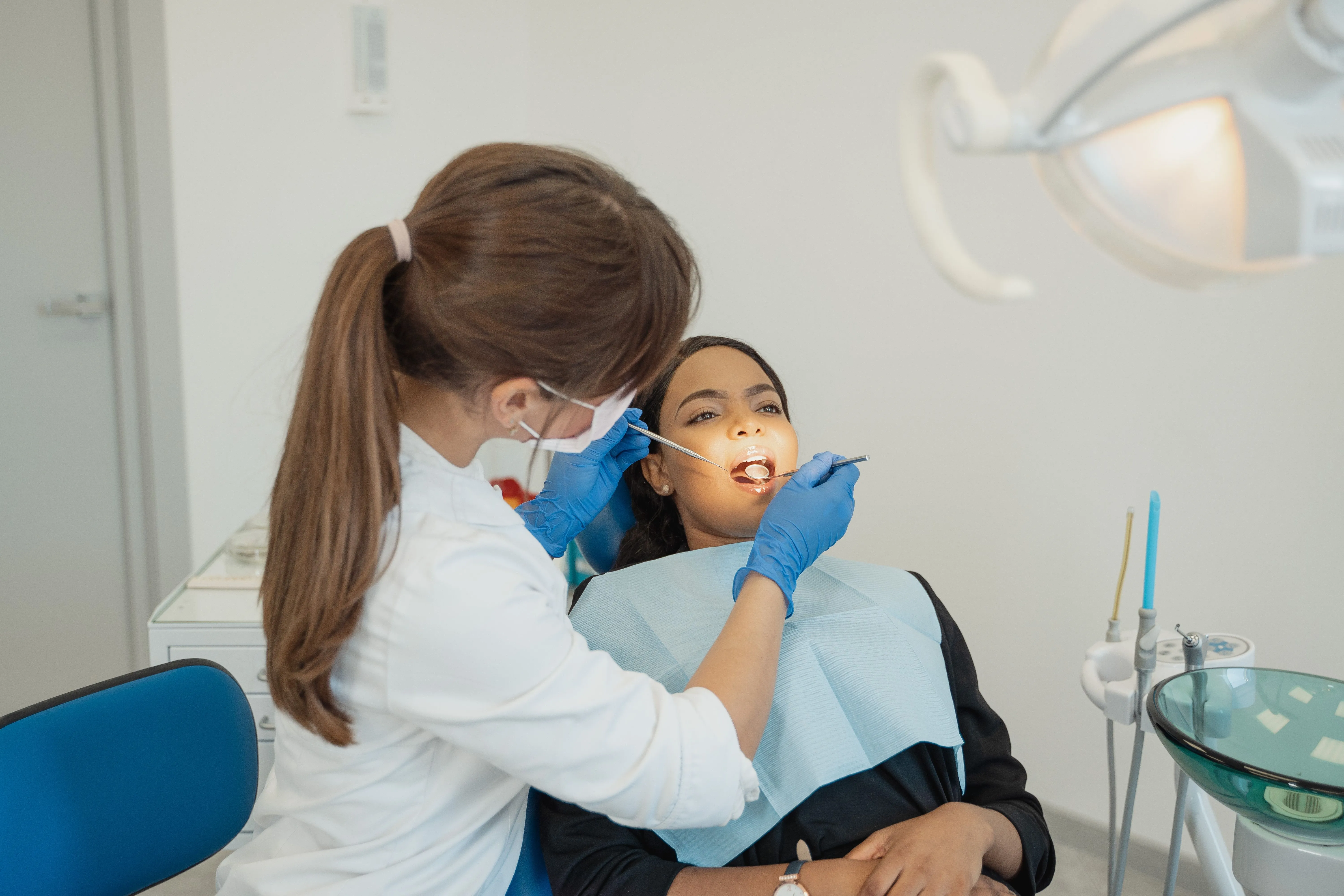 A dentist works on the mouth of a lady sitting in the dentist's chair