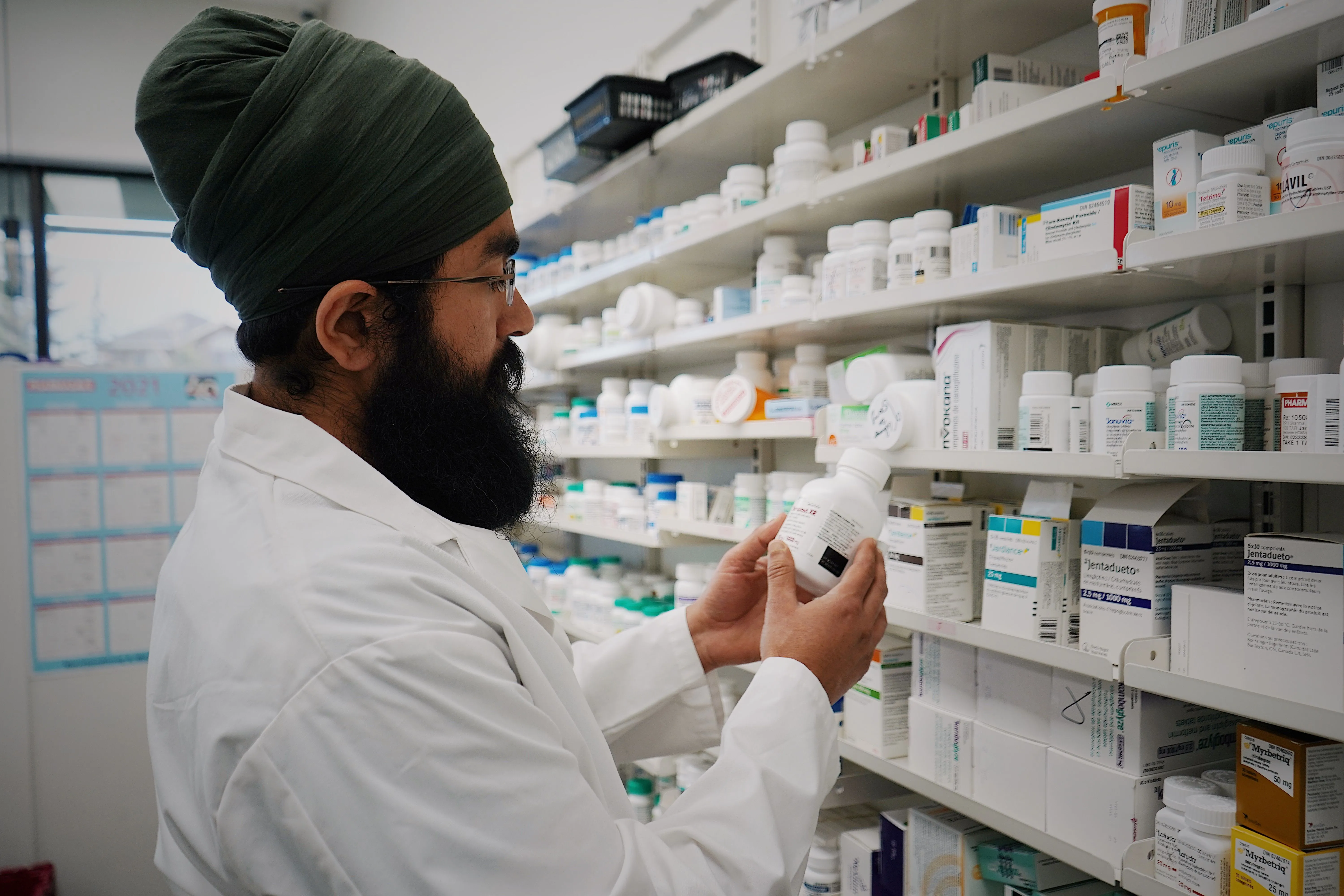 A pharmacist looks at medication in a pharmacy.