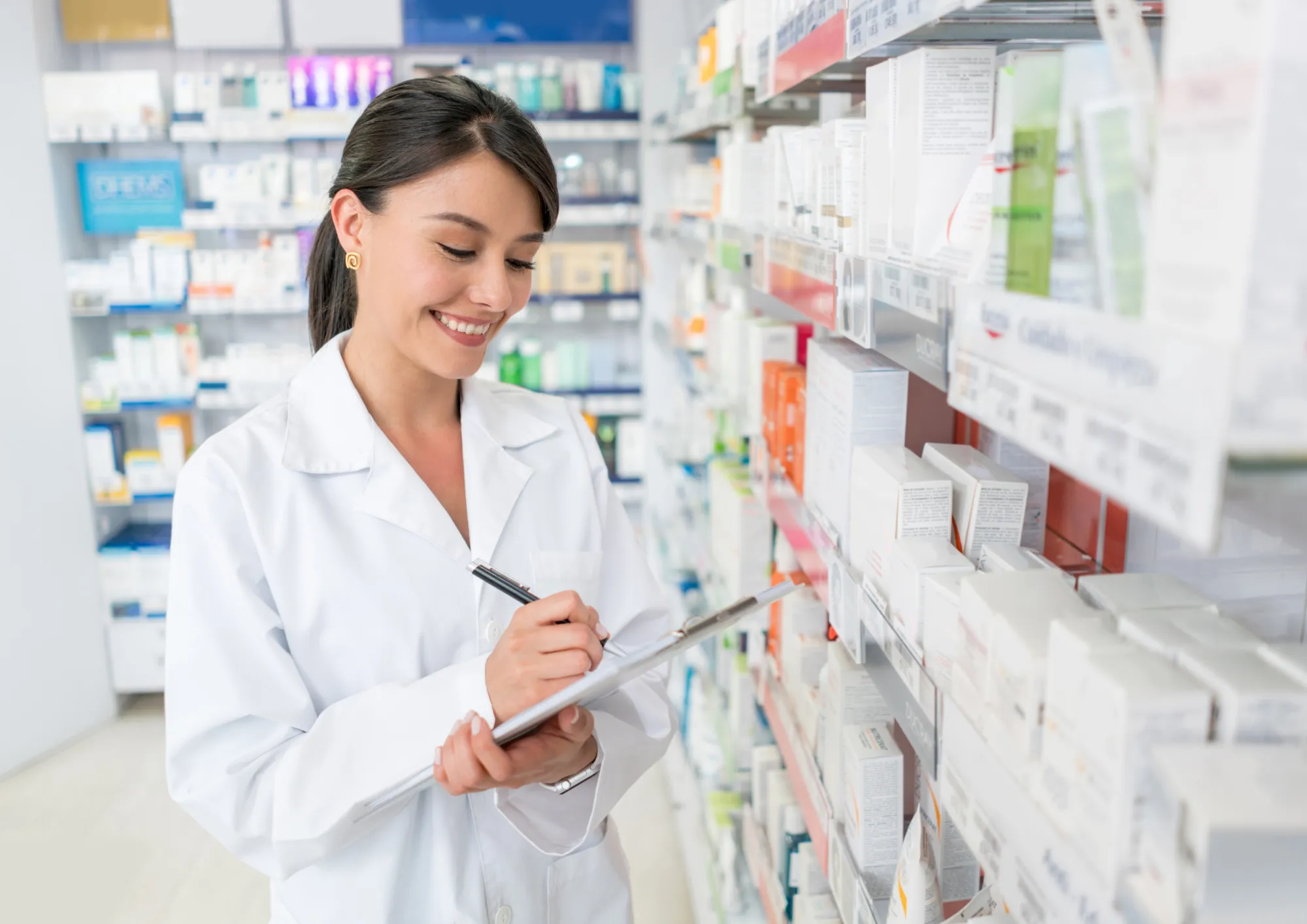 A pharmacist stands in front of a shelf of medications.