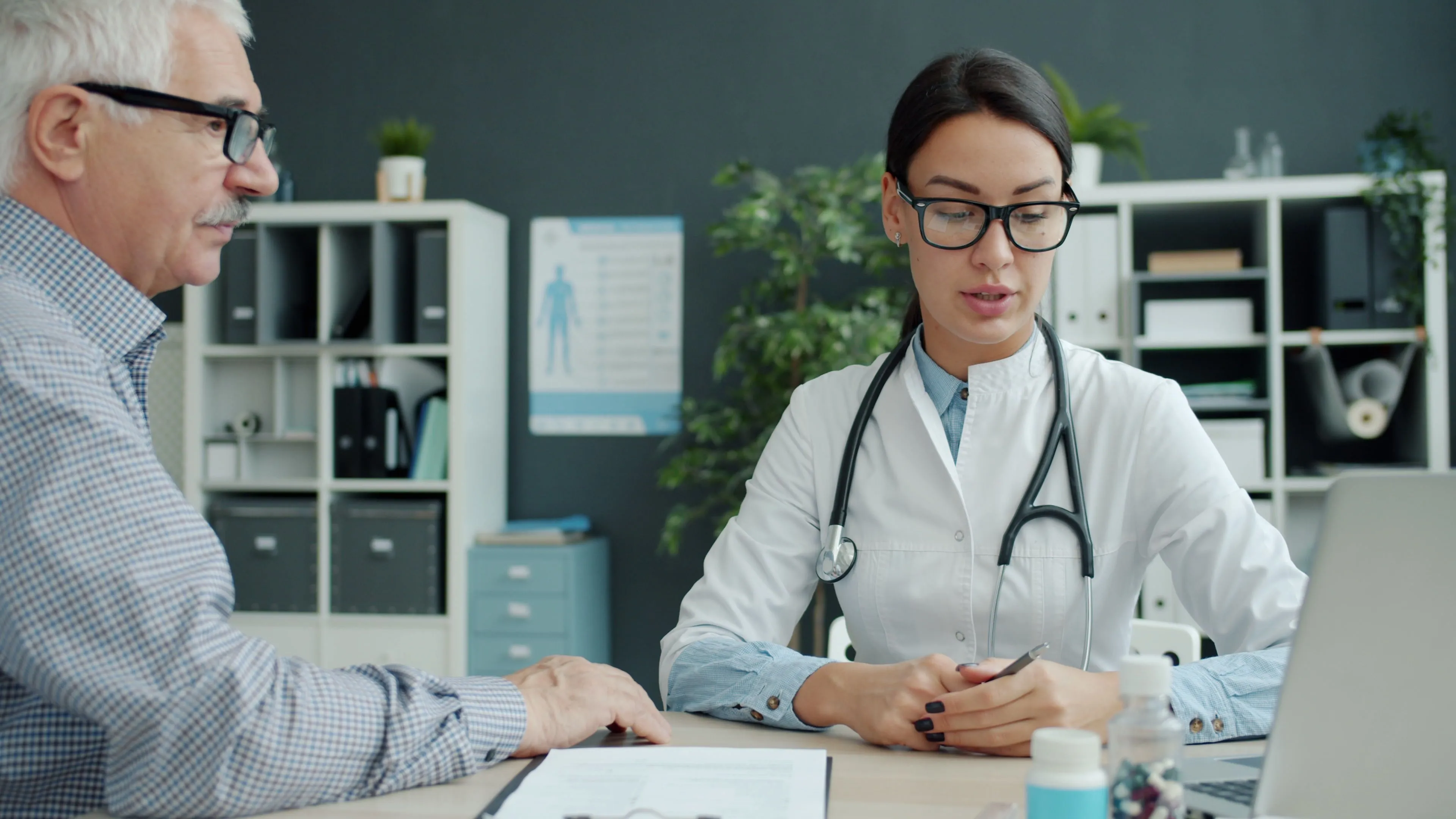A doctor sits at a desk across from a patient.