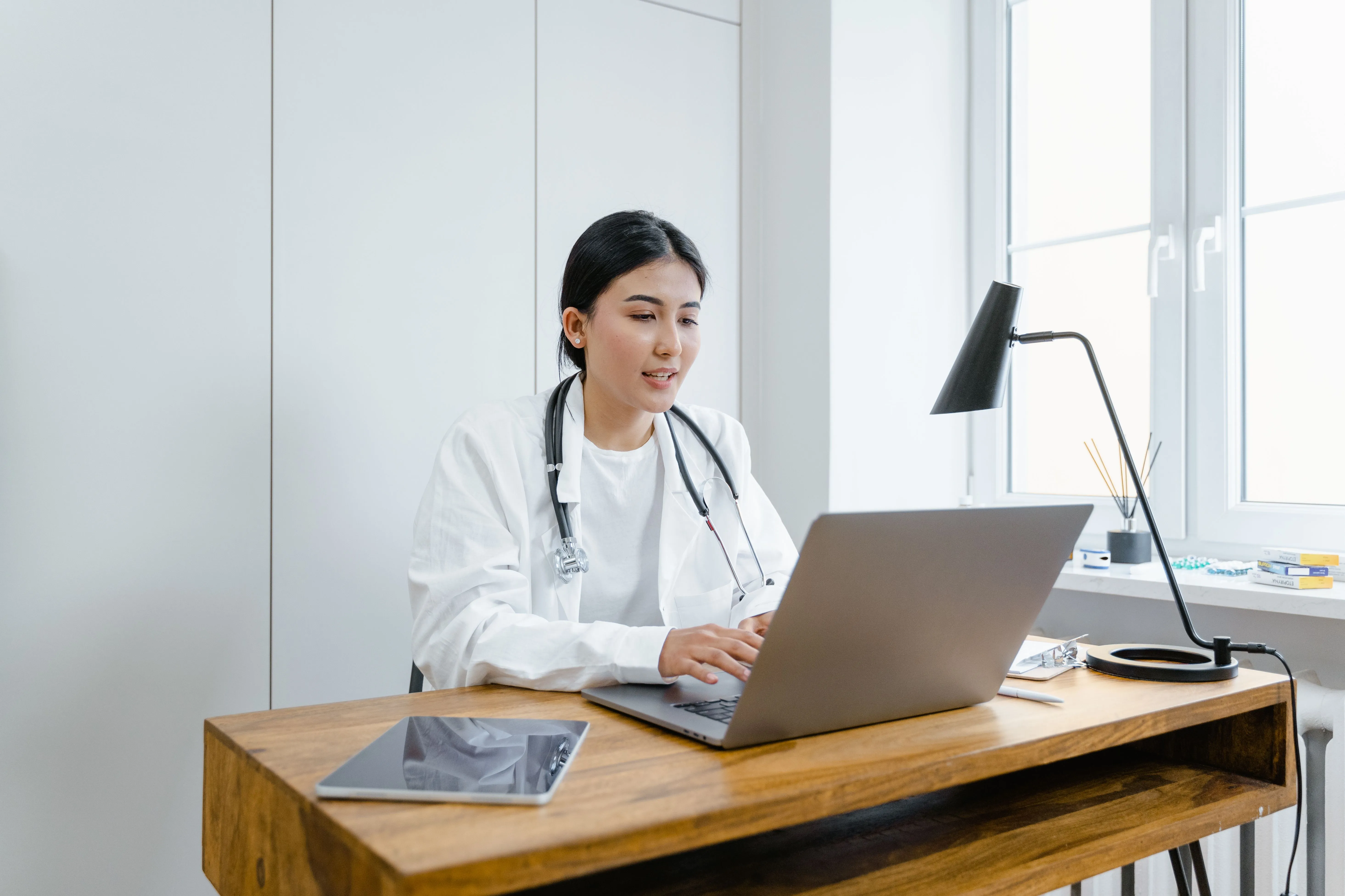 A doctor is looking at her laptop during a virtual doctor's appointment.