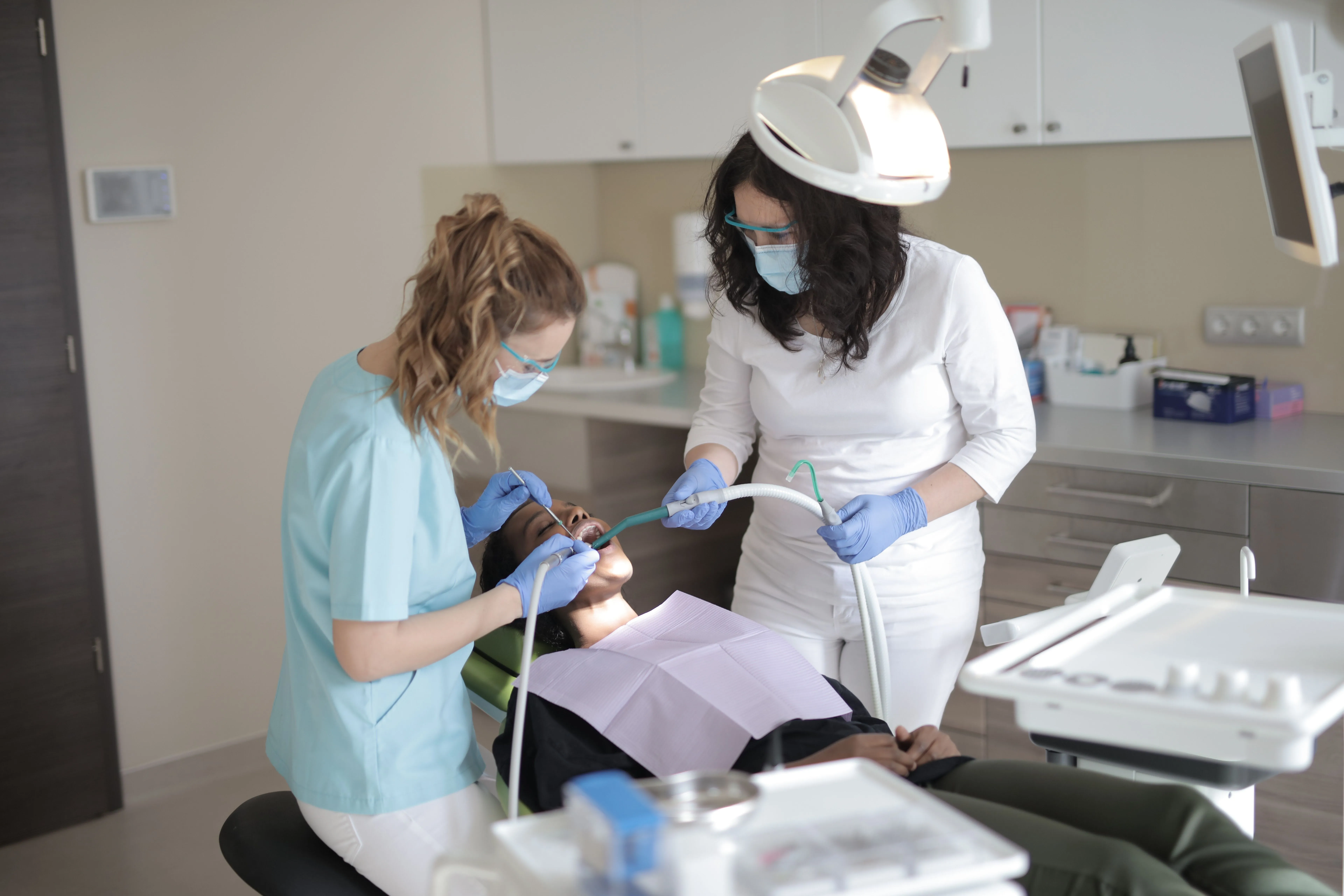 A dentist and hygienist work on a patient in a dentist's office. 