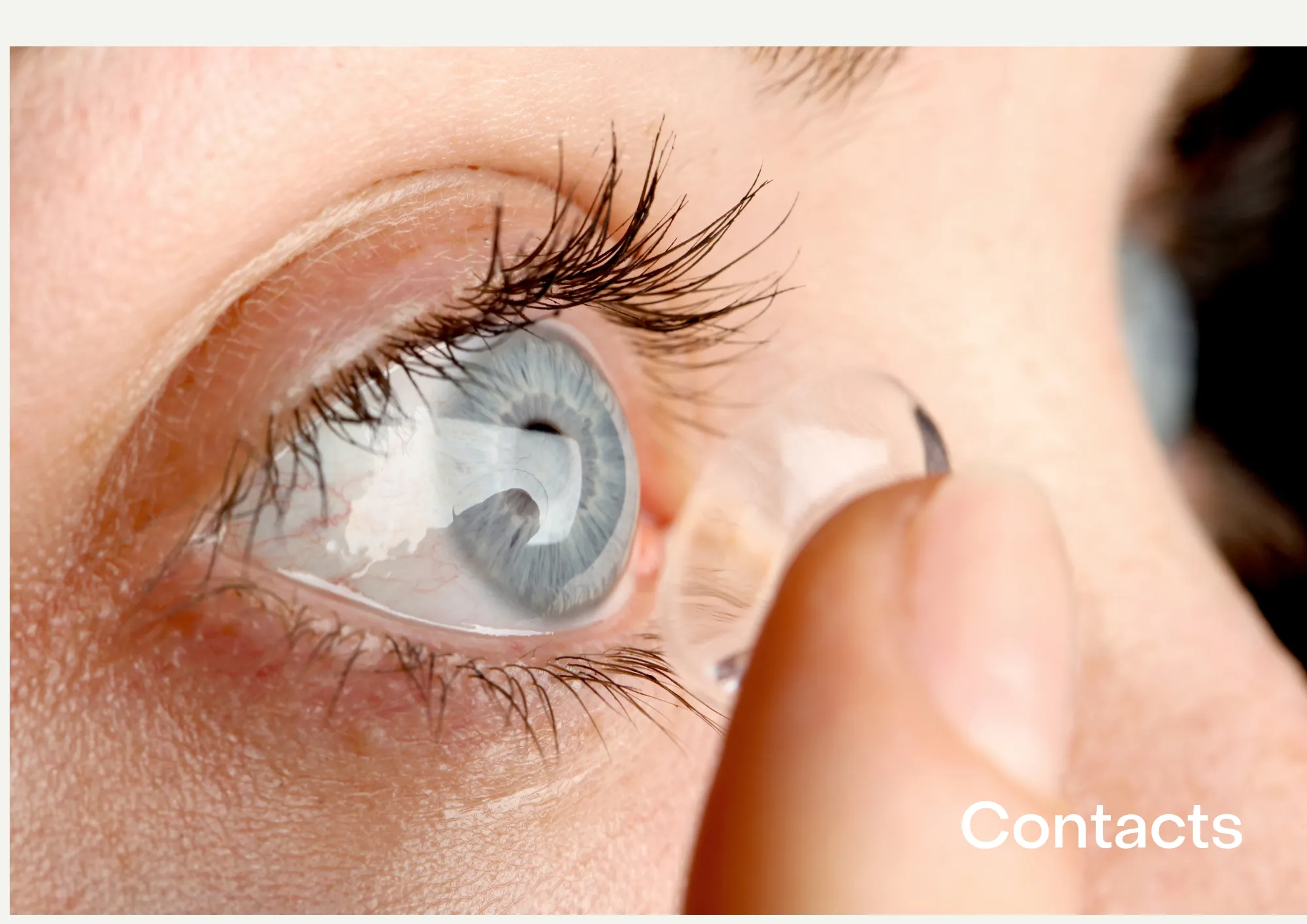 A blue-colored eye with a finger inserting a contact lens.