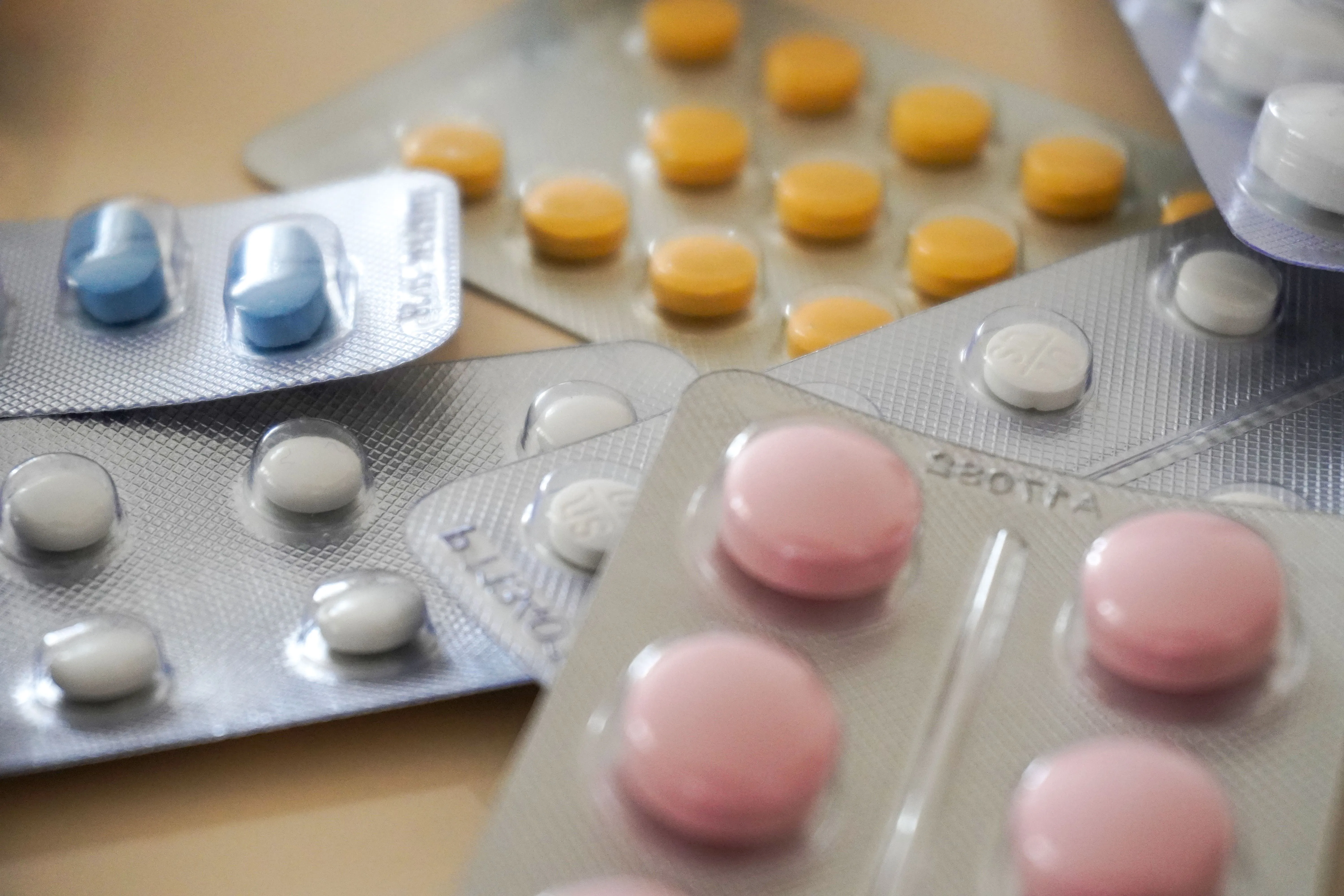 Different types of pills sit on a beige surface.