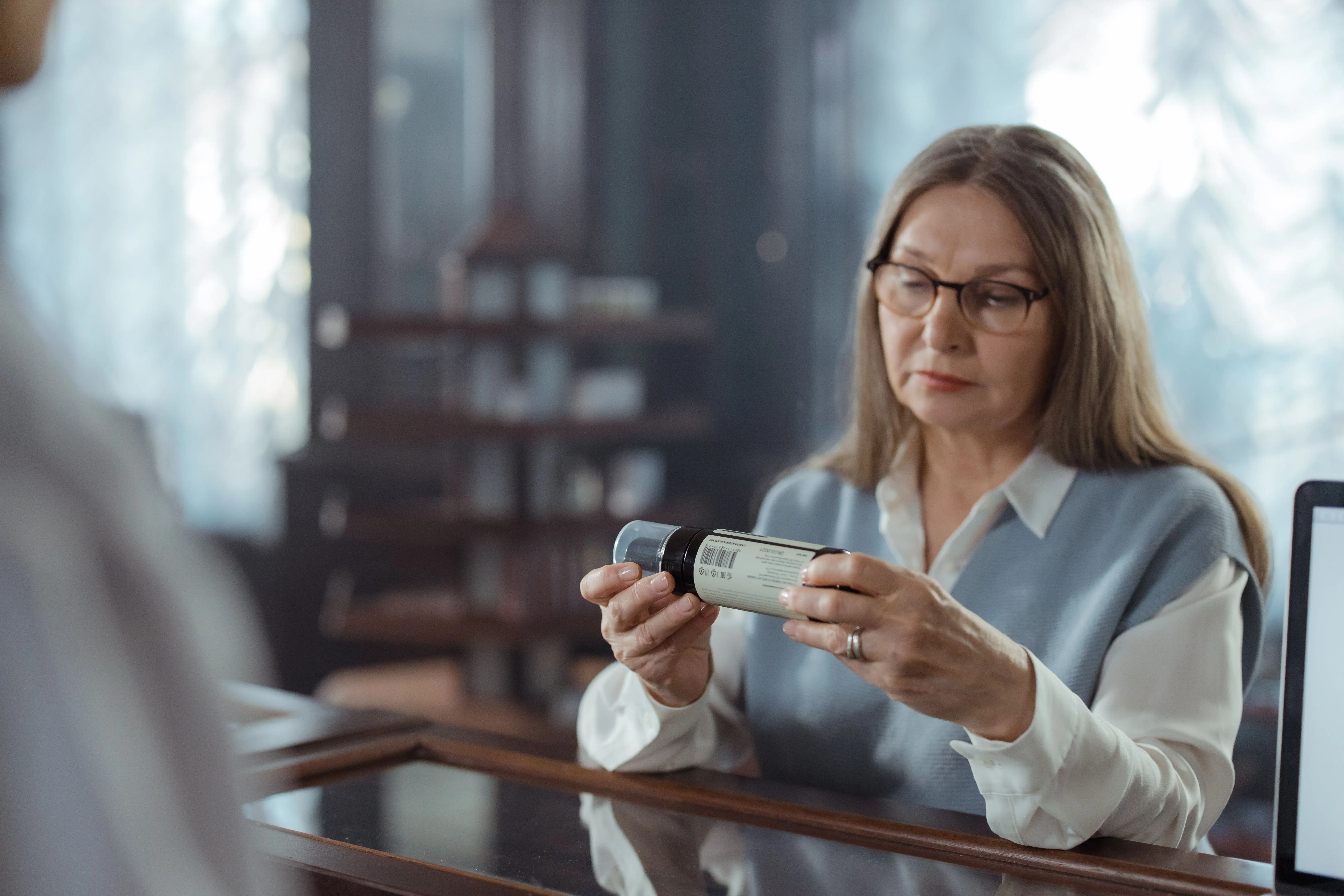 A lady looks at a bottle of medicine at the pharmacy.